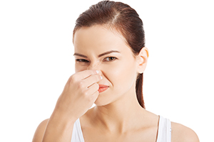 Portrait of a young woman holding her nose because of a bad smel